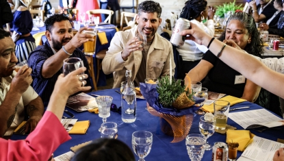  a group at a table celebrate by lifting their glasses to cheers.